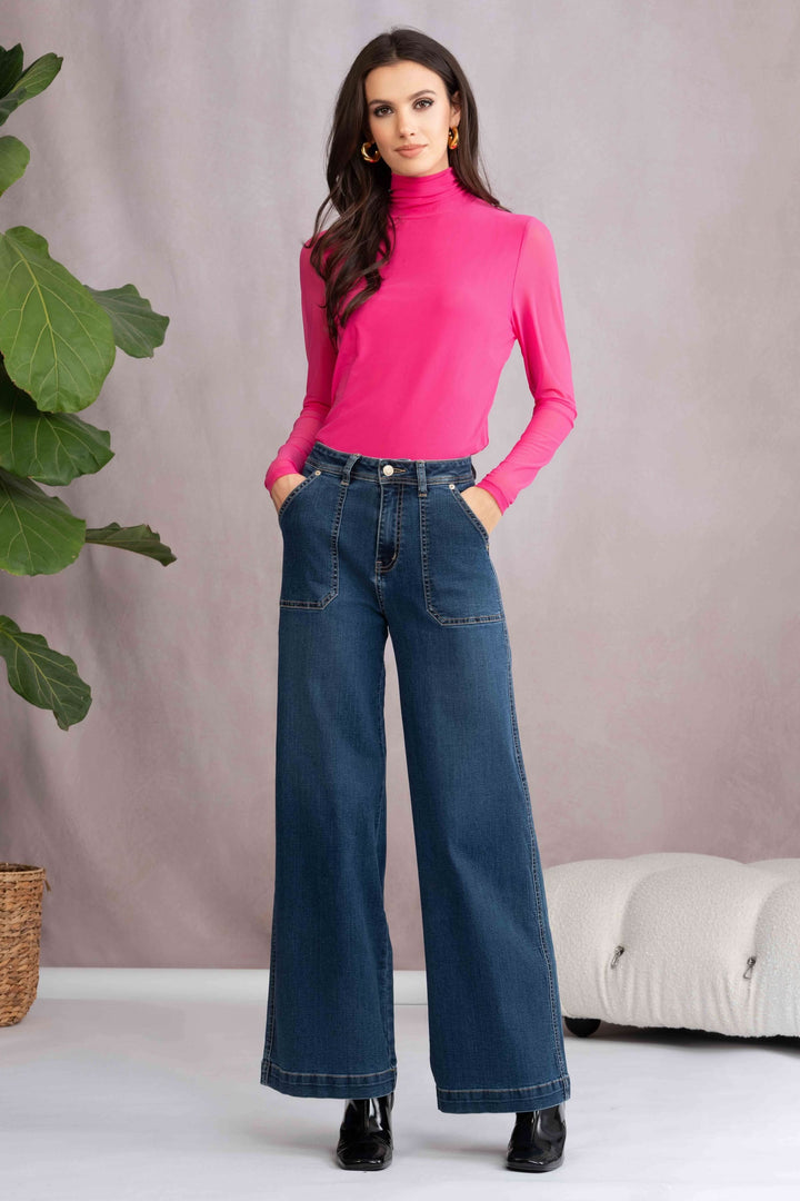 Femme portant un jean à jambes évasées avec un haut rose, style décontracté et moderne.