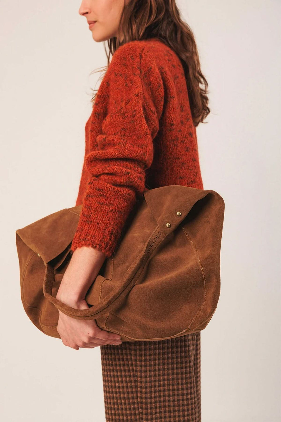 Femme portant un sac cabas en cuir suédé spacieux, parfait pour un look décontracté et raffiné avec un manteau long.