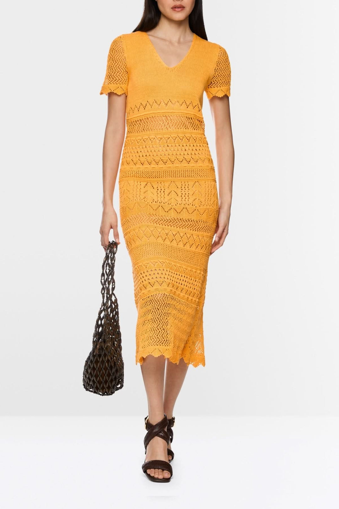 Femme portant une robe longue en maille ajourée à col v jaune, avec manches courtes, parfaite pour l'été et les journées ensoleillées.