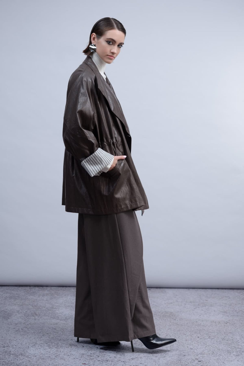 Vue de côté manteau similicuir noir Haako pour femme avec boutons apparents - Valérie Simon