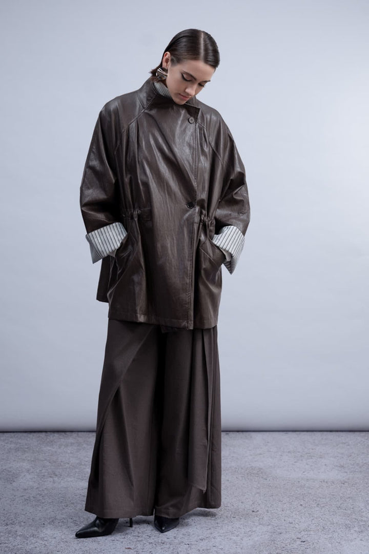 Vue de face manteau en similicuir Haako pour femme noir avec ceinture et boutonnière - Valérie Simon
