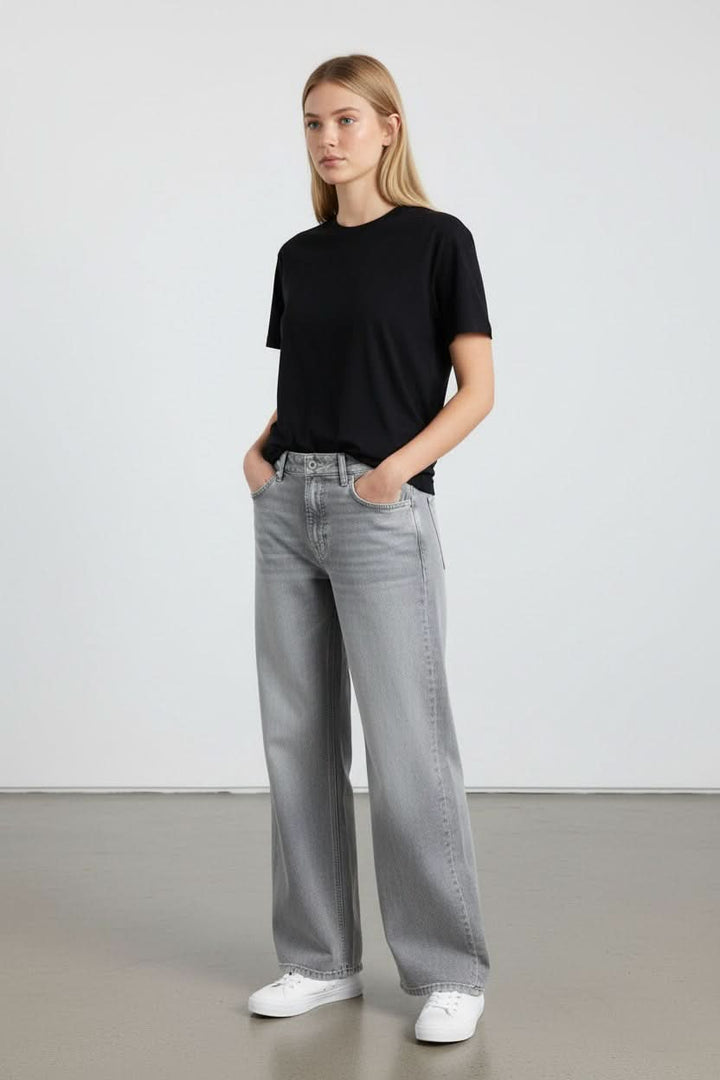 Femme portant Jeans jambe large Oria avec coupe large et détails élégants, idéal pour un look contemporain et décontracté.