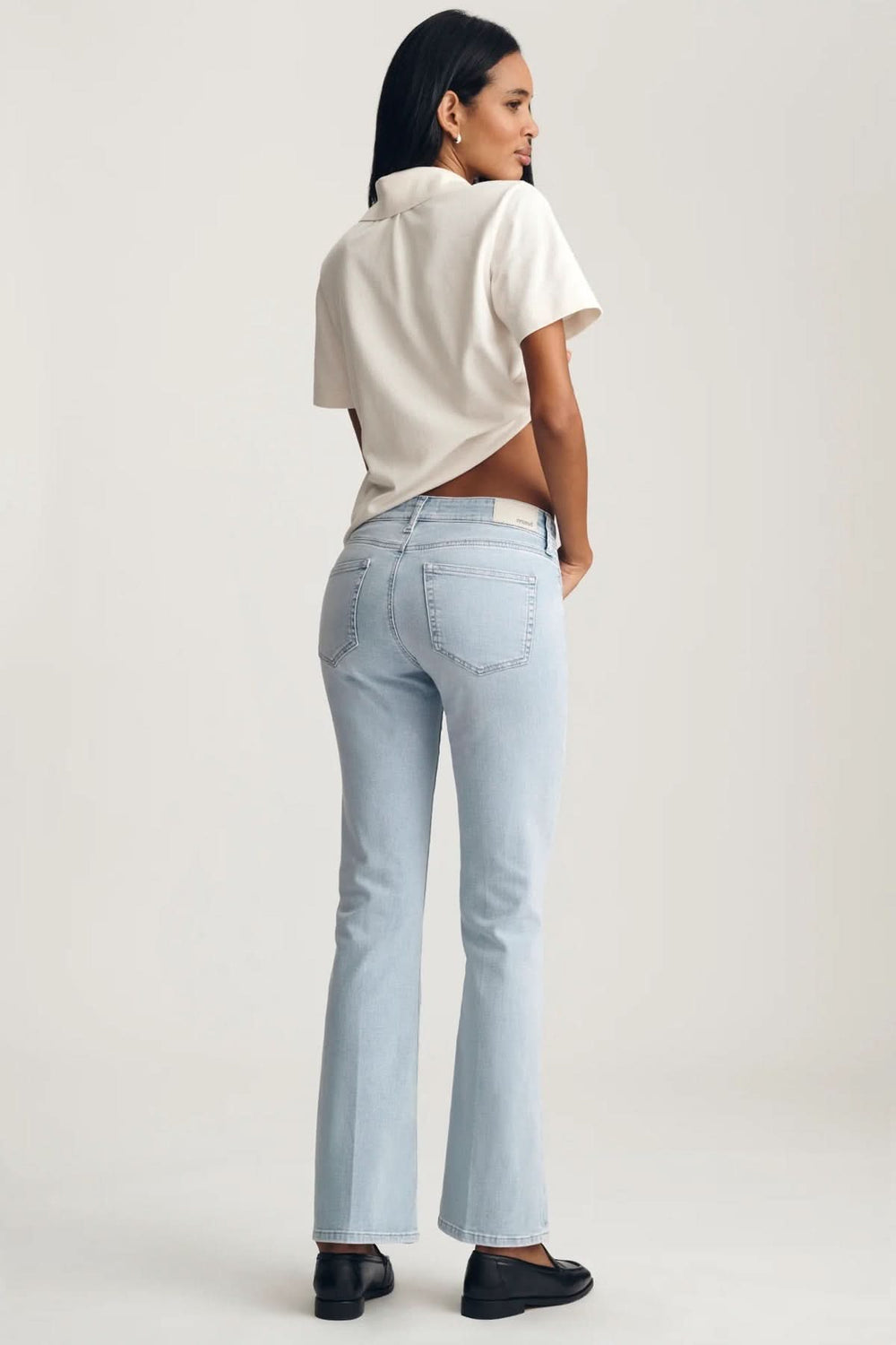 Femme portant Jeans Vicky coupe droite longueur cheville, vue arrière, avec un t-shirt blanc et des chaussures noires sur fond blanc.