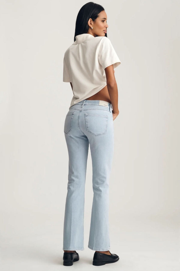 Femme portant Jeans Vicky coupe droite longueur cheville, vue arrière, avec un t-shirt blanc et des chaussures noires sur fond blanc.