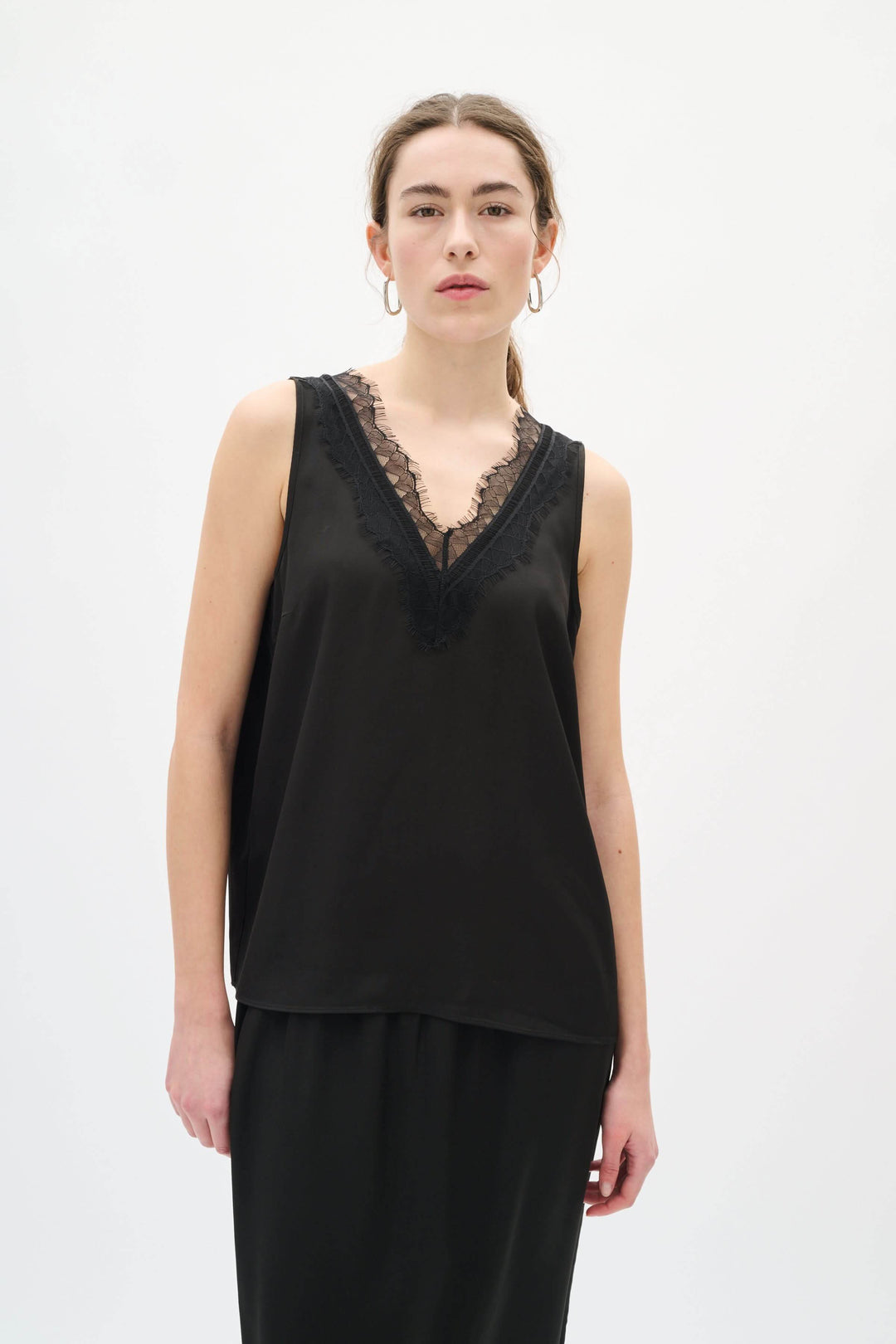 Camisole Danica en satin à encolure dentelle, femme portant haut noir en satin avec dentelle, look chic et intemporel