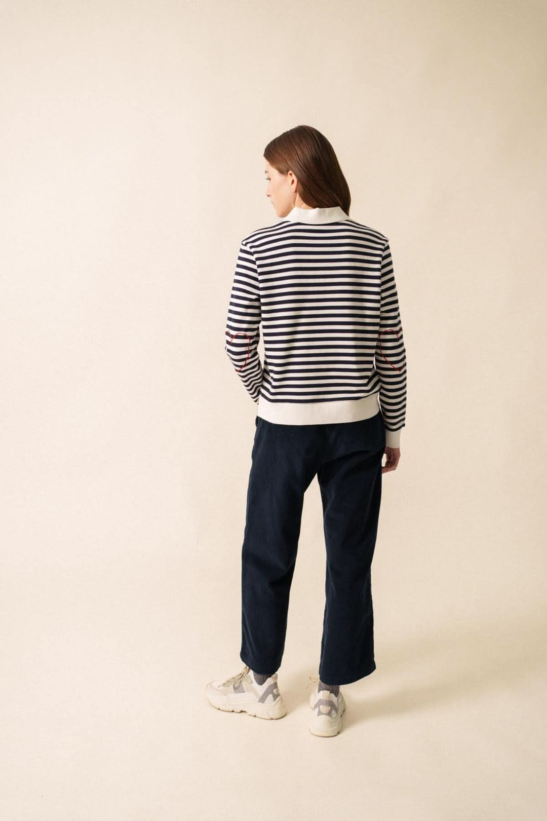 Femme portant un chandail polo NINA en molleton rayé, vu de dos, avec un look décontracté et féminin.