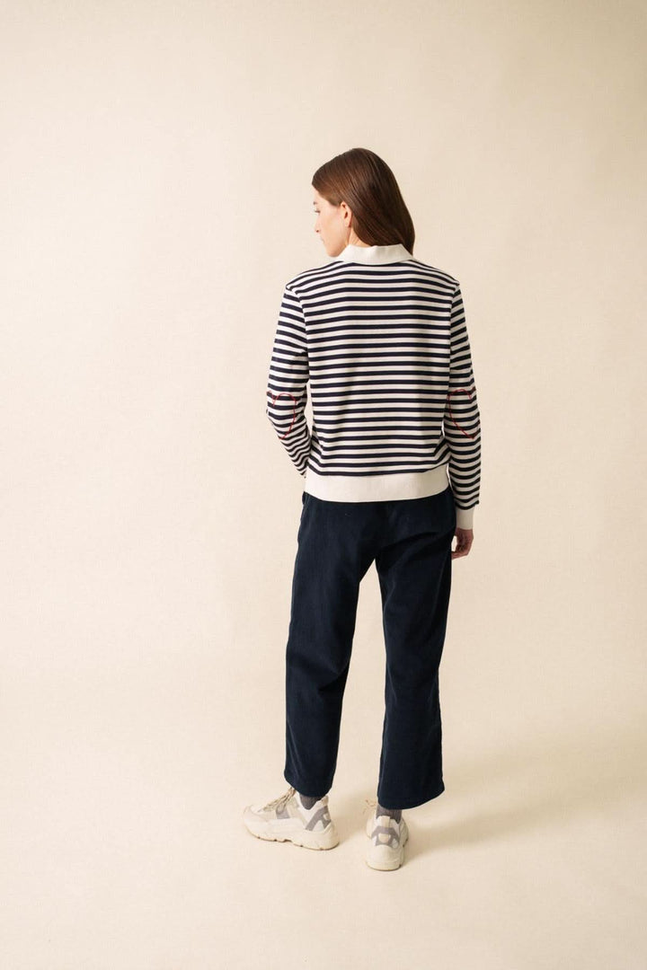 Femme portant un chandail polo NINA en molleton rayé, vu de dos, avec un look décontracté et féminin.