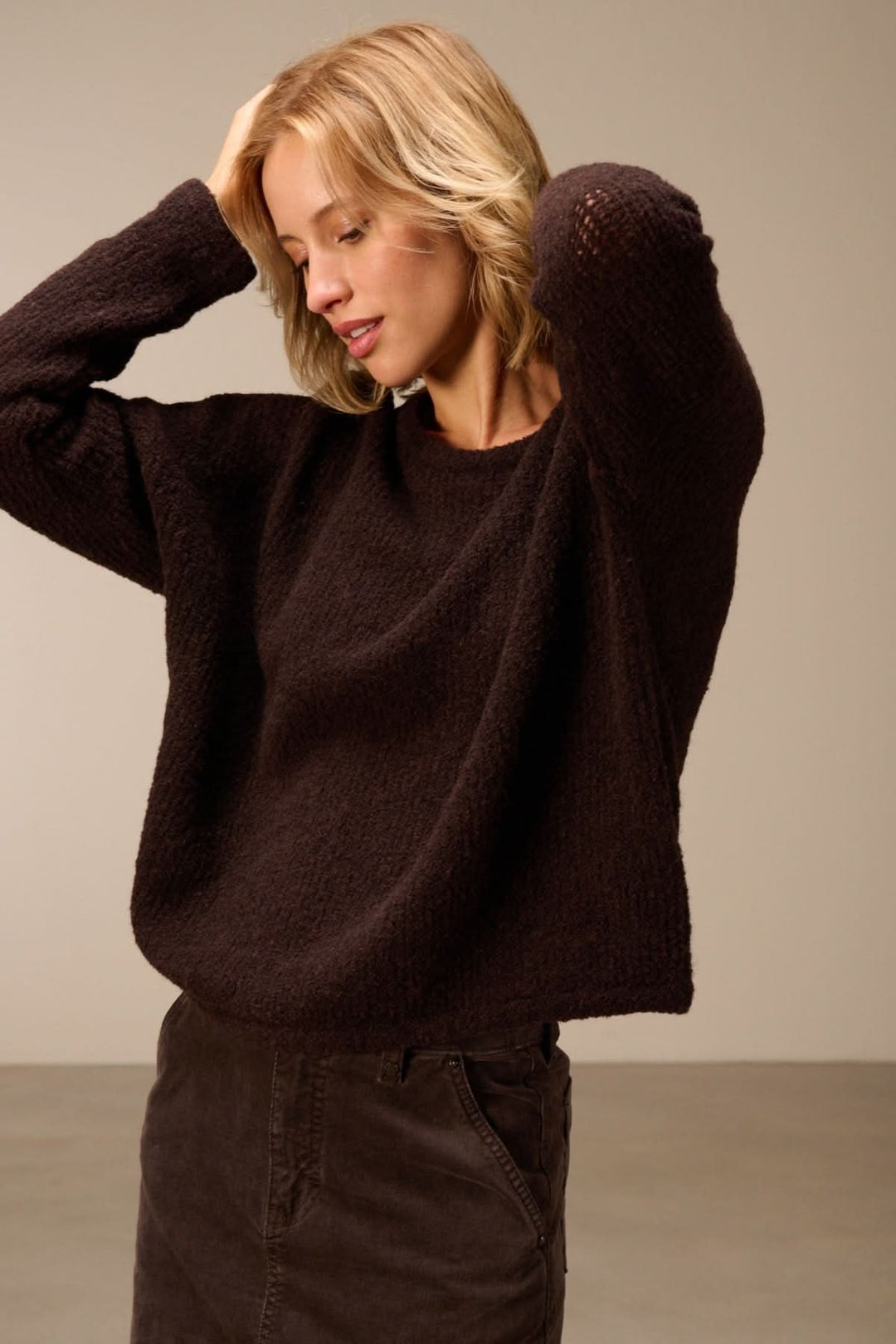 Femme portant un chandail ample en laine mérinos texturée avec manches longues et col rond, créant une allure moderne et confortable.