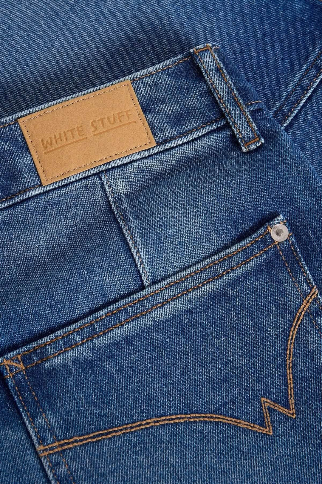 Détails du tissu en denim bleu, logo White Stuff sur l'étiquette, et surpiqûres contrastées sur la poche.