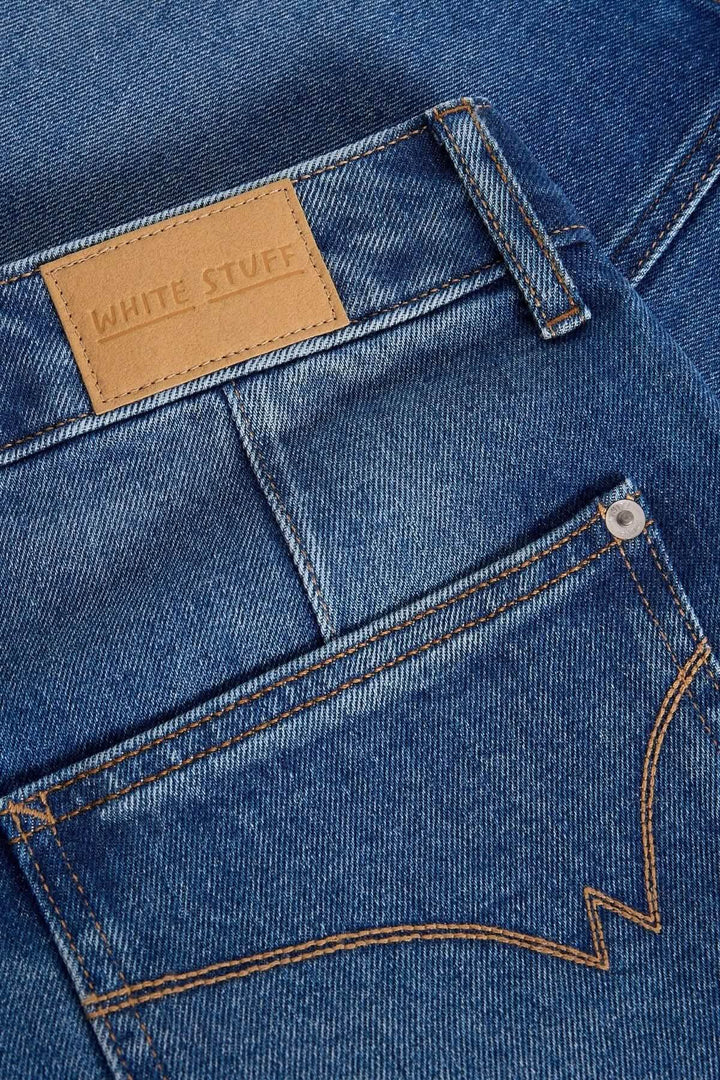 Détails du tissu en denim bleu, logo White Stuff sur l'étiquette, et surpiqûres contrastées sur la poche.