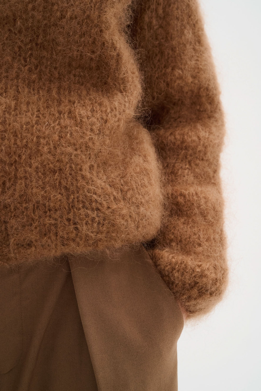 Chandail en maille duveteuse brune avec texture douce, porté avec un pantalon beige, style cosy et élégant.