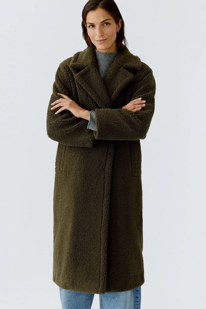 Manteau long en tissu bouclette moderne et douillet, idéal pour les journées froides, porté sur un jean. Style élégant et confortable.