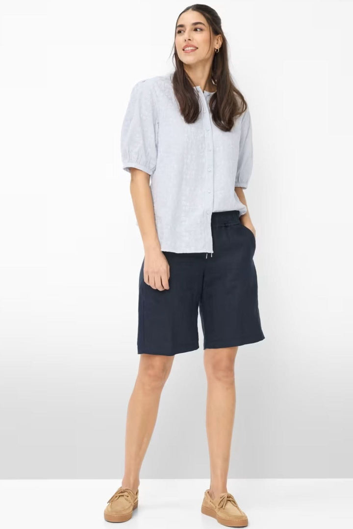 Femme portant des Bermudas en lin MEL B, style décontracté avec chemise et sandales.