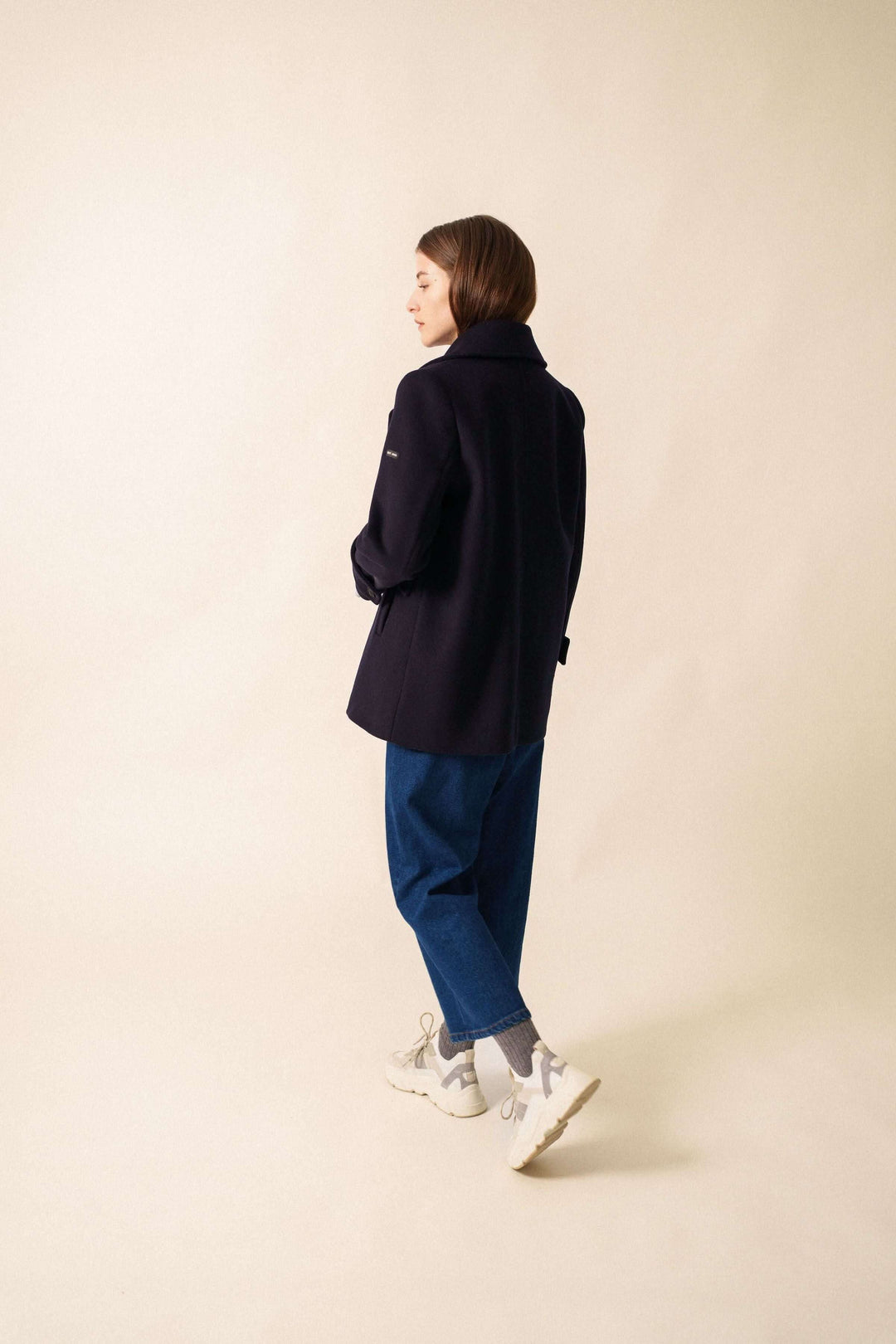 Manteau chic en longueur sous les fesses avec encolure en V, porté avec un look décontracté et élégant.