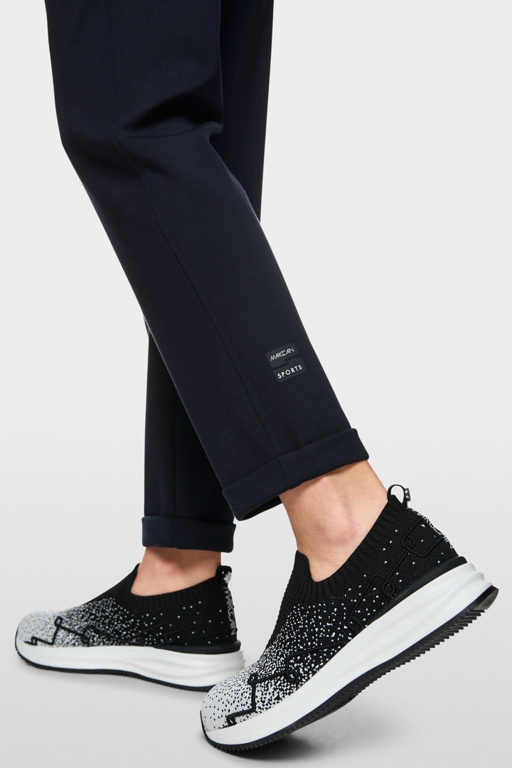 Pantalon jogger Rhodos avec revers, porté avec des sneakers modernes en noir et blanc.