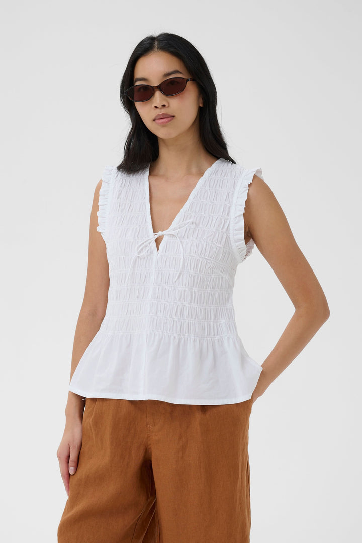 Blouse Borgny smockée sans manches à encolure nouée portée par une femme.