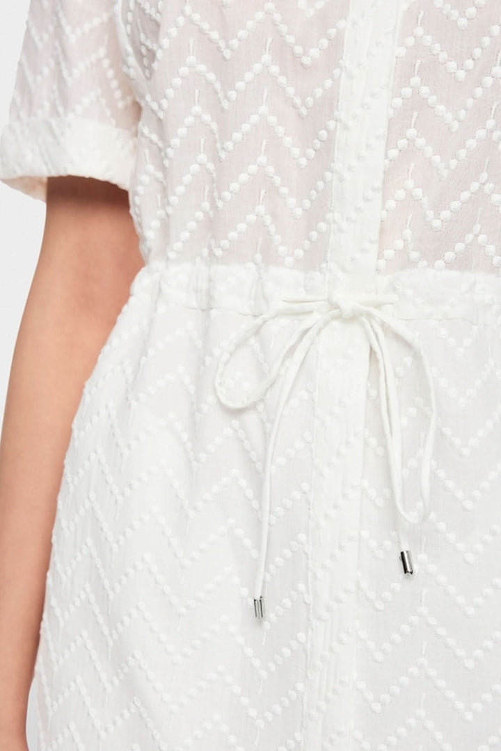 Détail de la robe en coton avec cordon à la taille pour un style élégant et confortable.