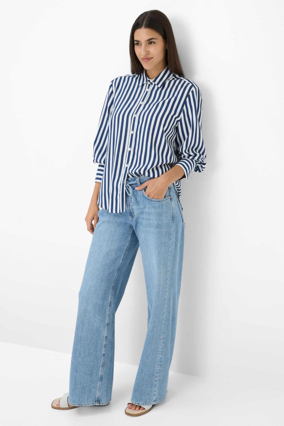 Chemise à rayures verticales, moderne et élégante, portée avec un jean clair pour une tenue raffinée.