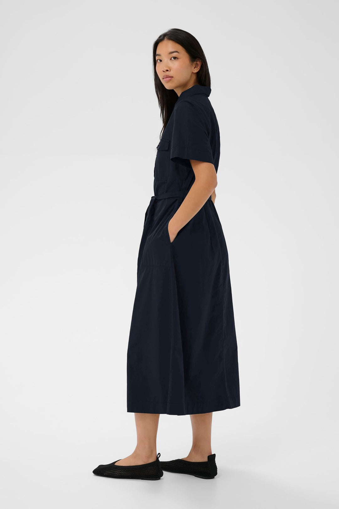 Femme portant la Robe Ariel chemise longue ceinturée manches courtes, élégante et structurée, avec ceinture et manches courtes.
