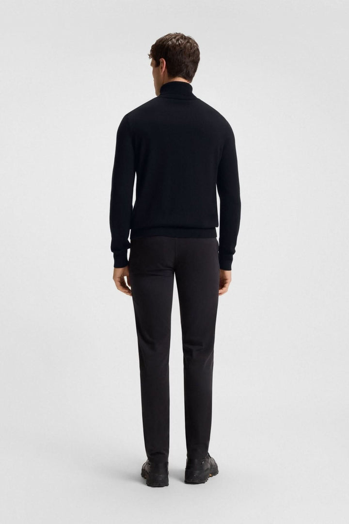 Homme portant un col roulé coton et cachemire Boss Orange noir avec pantalons habillés, vue de dos pour un look élégant et moderne.