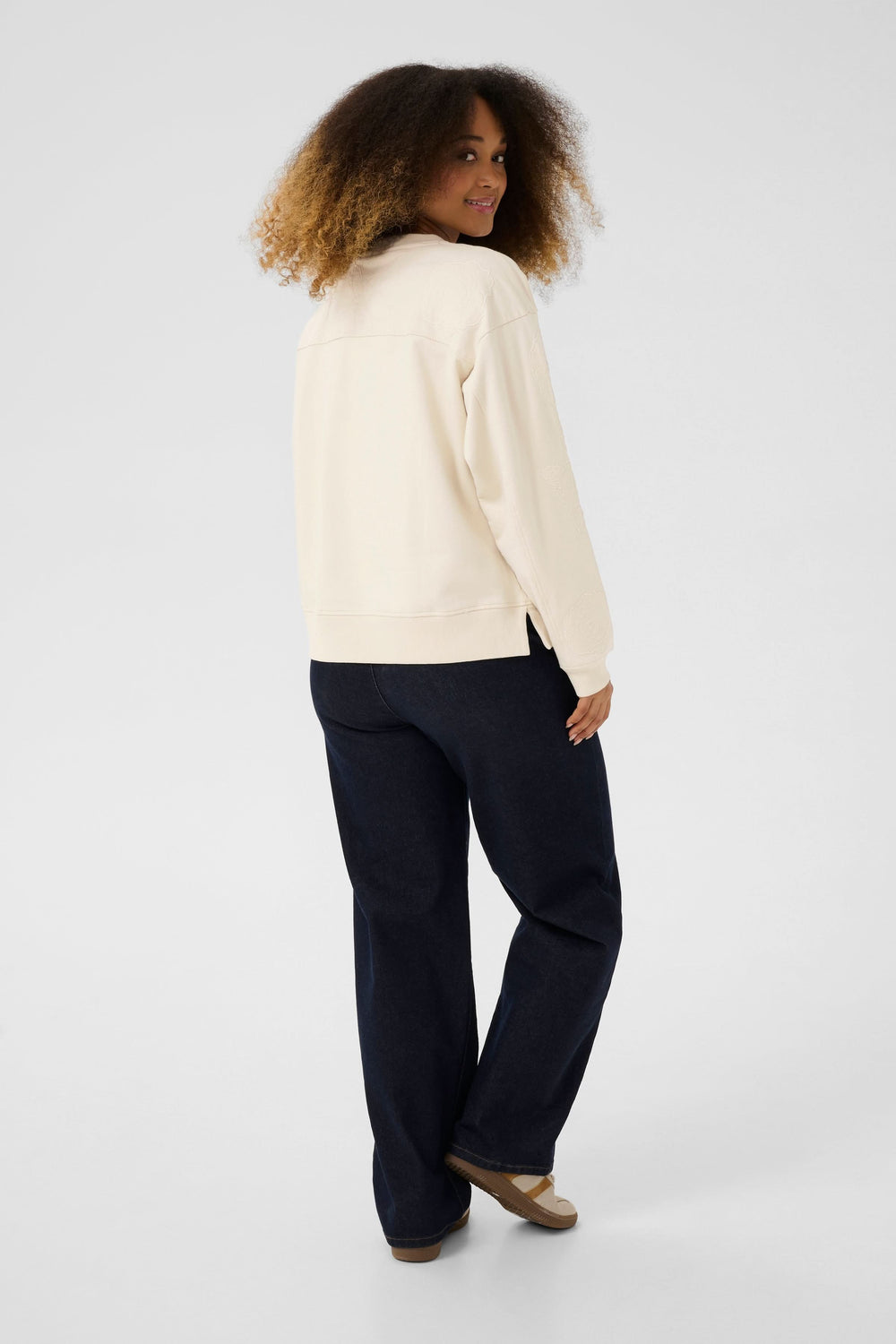 Femme portant un coton ouaté Josie crème, vue de dos avec un pantalon foncé, style décontracté et chic.