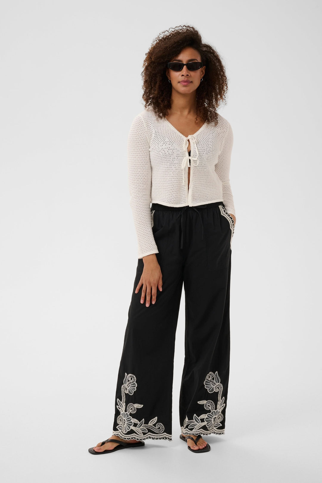 Cardigan Rosefina en maille ajourée à nouer, léger et féminin, avec fermeture à nouer devant. Coupe ajustée pour confort et style.