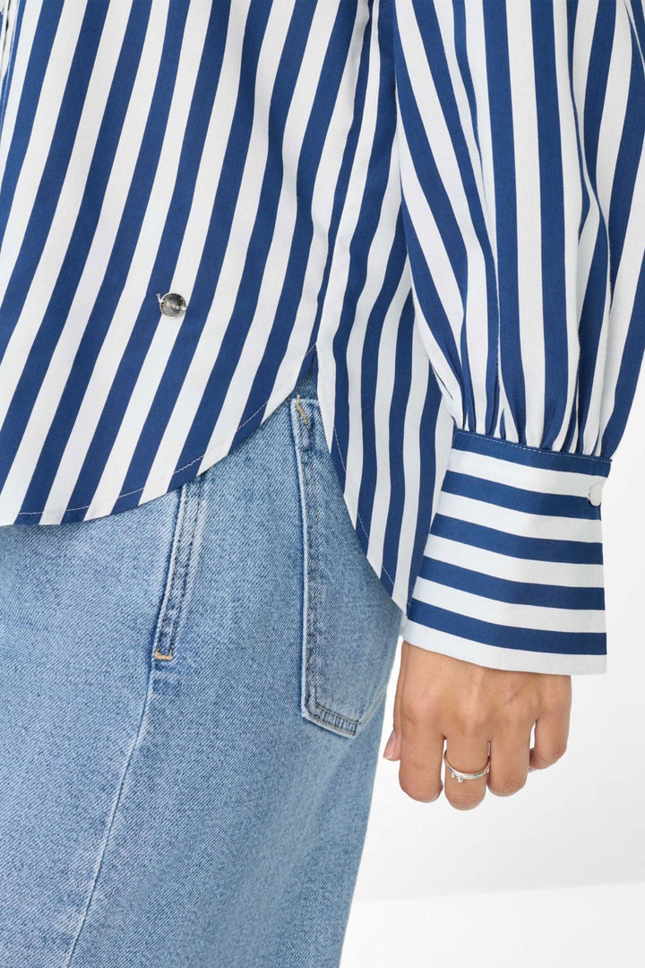 Blouse à rayures verticales bleu et blanc, coupe légèrement évasée, manches à poignets larges.