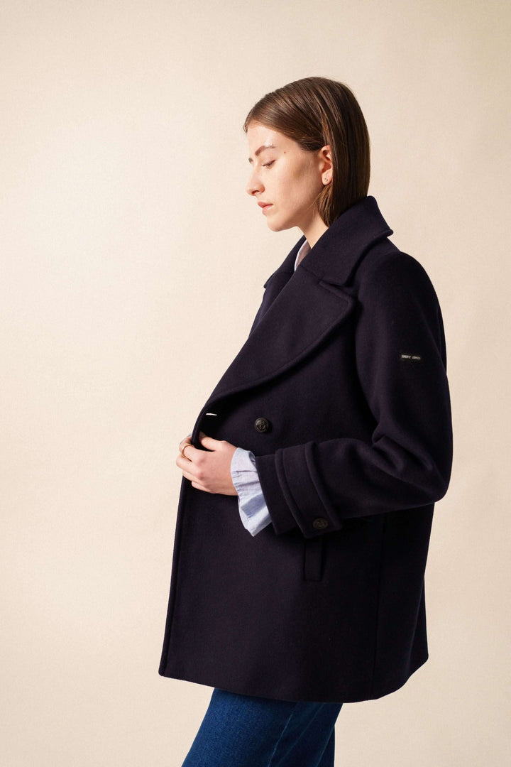 Manteau chic de longueur sous les fesses, encolure en V, boutons avant et poches pratiques, porté de profil.