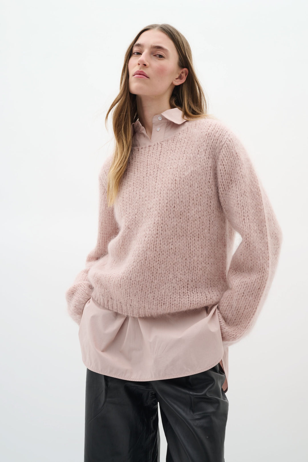 Chandail Jetra en maille duveteuse rose, porté avec une chemise, créant un look cosy et élégant.