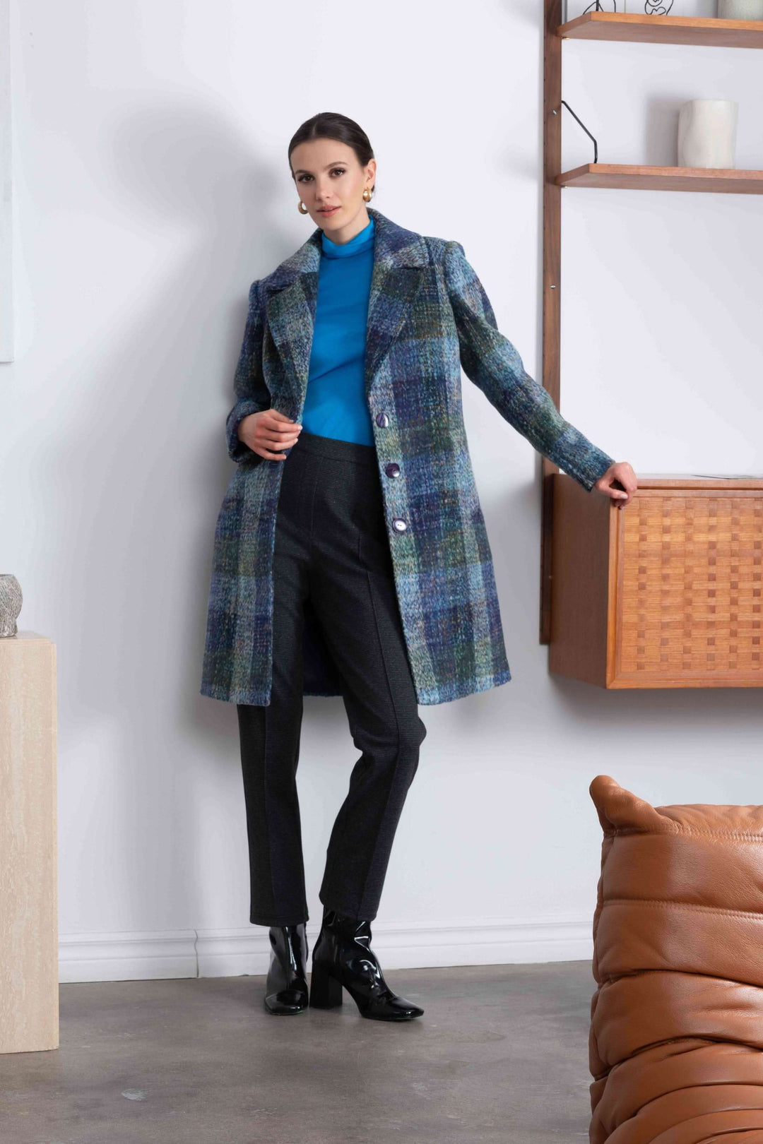 Manteau à carreaux mi-long avec col à revers, porté sur un pull bleu et pantalon noir, style élégant et intemporel.