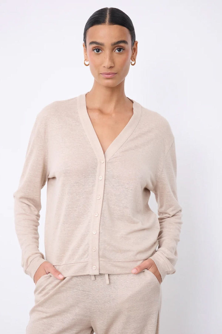 Femme portant un cardigan col v boutonné léger beige, manches longues, coupe fluide.