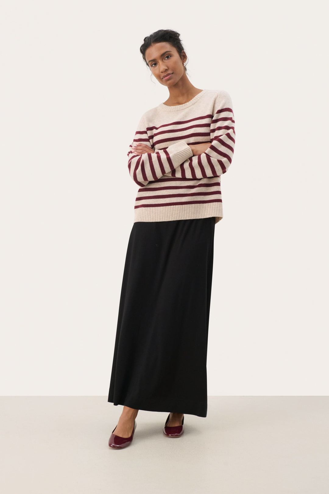 Chandail Niaka doux à rayures, encolure ronde, porté avec une jupe noire pour un look décontracté et raffiné.