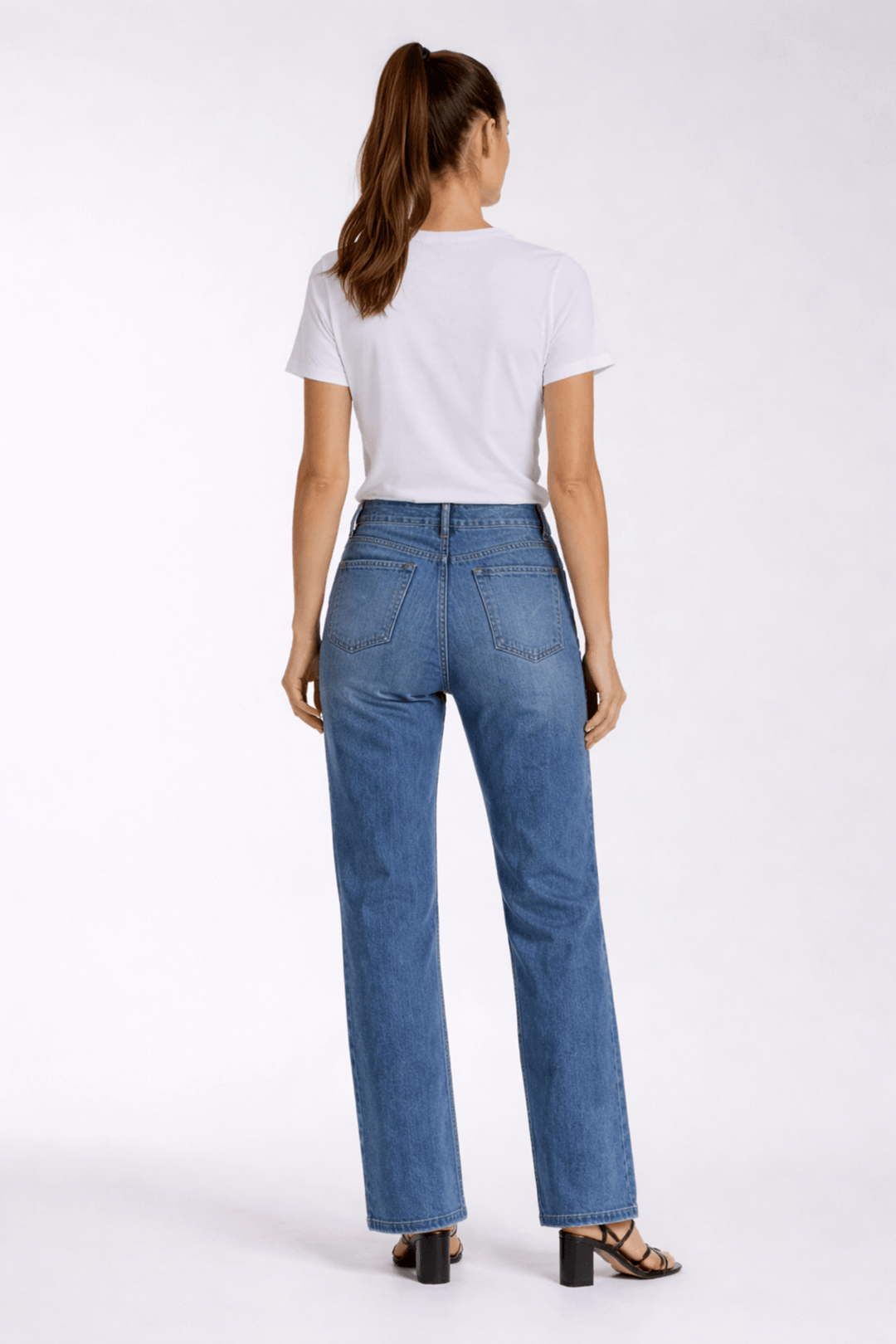 Jeans coupe droite en denim bleu avec taille mi-haute, porté avec un t-shirt blanc, vue de dos. Décris moi le produit en français.