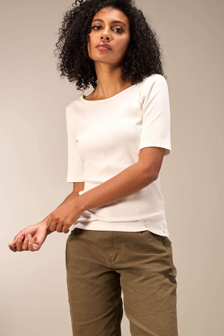 Chandail minimaliste à manches courtes, coupe ajustée, porté avec un pantalon beige, style simple et élégant.