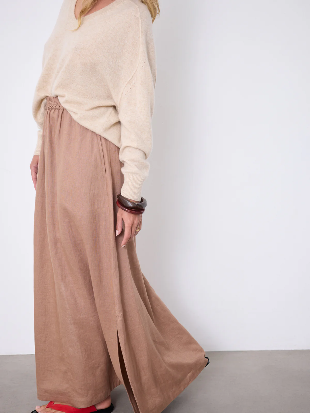 Jupe Vivienne longue fluide taille élastique portée avec un pull beige, mettant en valeur sa coupe élégante.