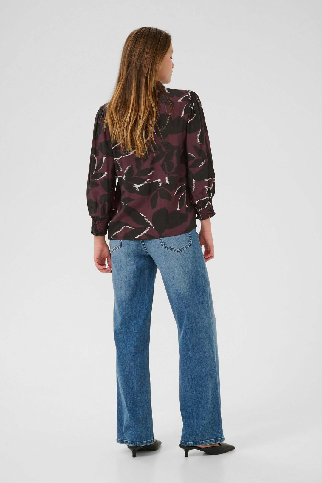 Chemise Mille imprimée à manches longues et poignets smockés vue de dos, portée avec un jean pour un look moderne et élégant.