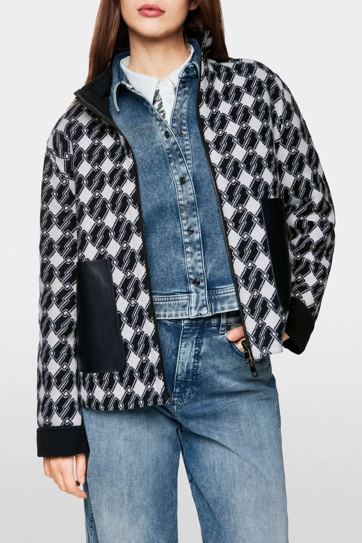 Veste à motif graphique avec imprimé géométrique, coupe droite et poches en simili cuir, portée sur un ensemble en denim.