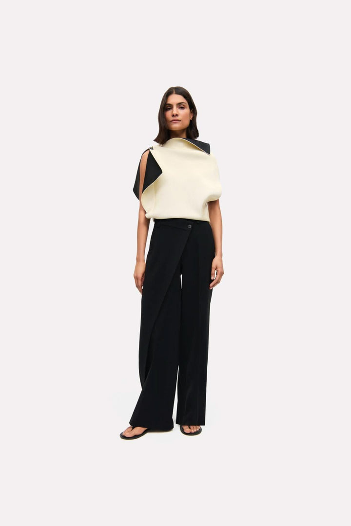 Femme portant un pantalon Anais à jambe large avec une blouse moderne, offrant une silhouette fluide et élégante.