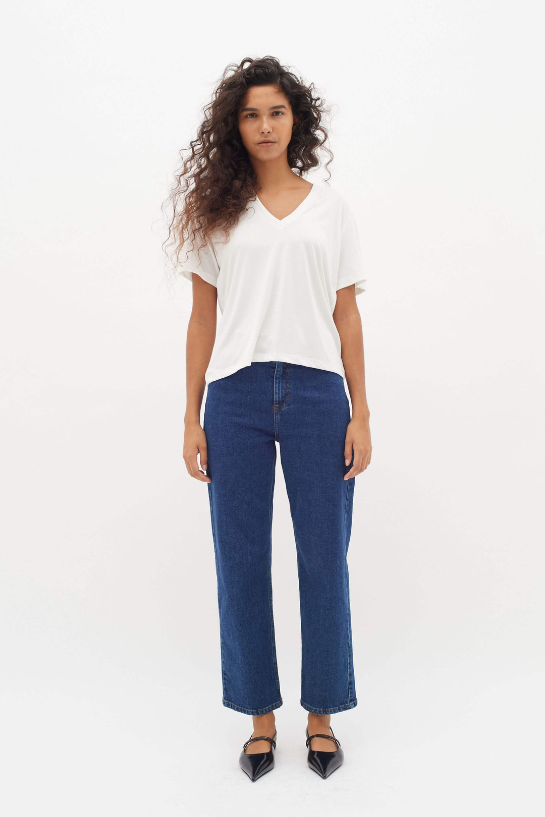 Femme portant un T-shirt col en V Liliana blanc, coupe droite et confortable, modernité et élégance pour un style quotidien.