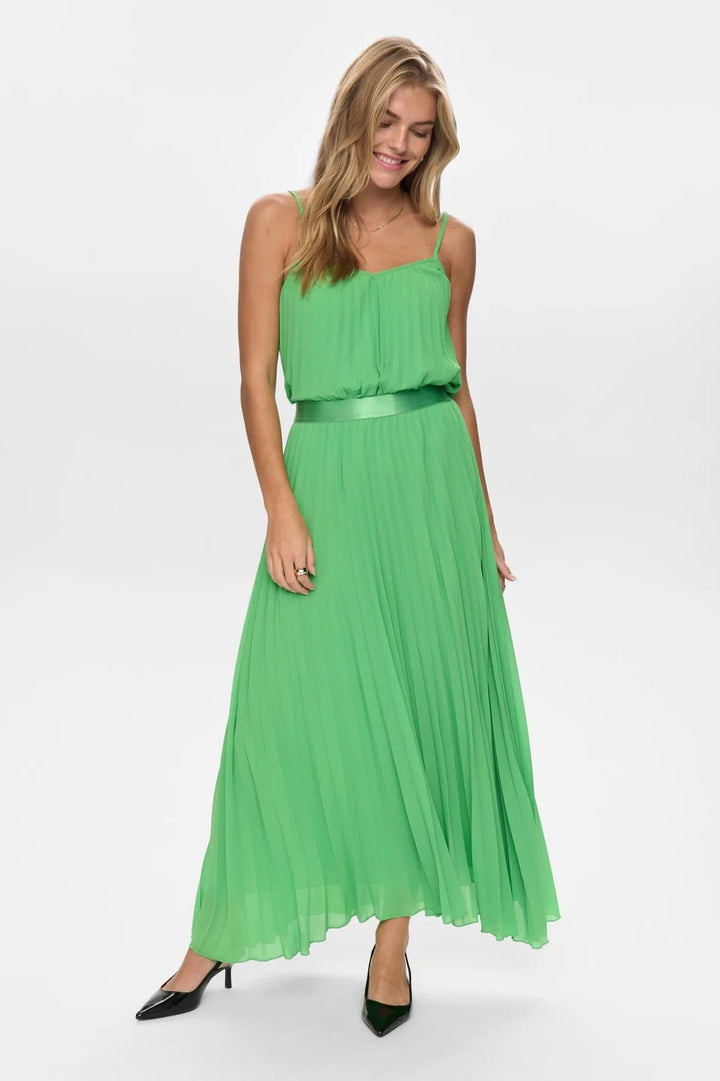 Femme portant une jupe longue plissée à fines bretelles verte, élégante et vaporeuse, avec une taille marquée pour une silhouette féminine.