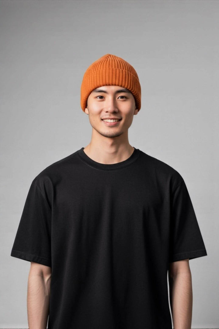 Person wearing an orange tuque en laine mérinos côtelée, showcasing its ribbed texture and cozy style for winter.