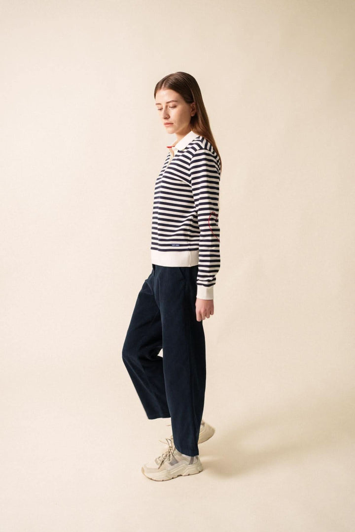 Polo NINA en molleton rayé avec coupe droite, porté avec un pantalon décontracté pour un look féminin.