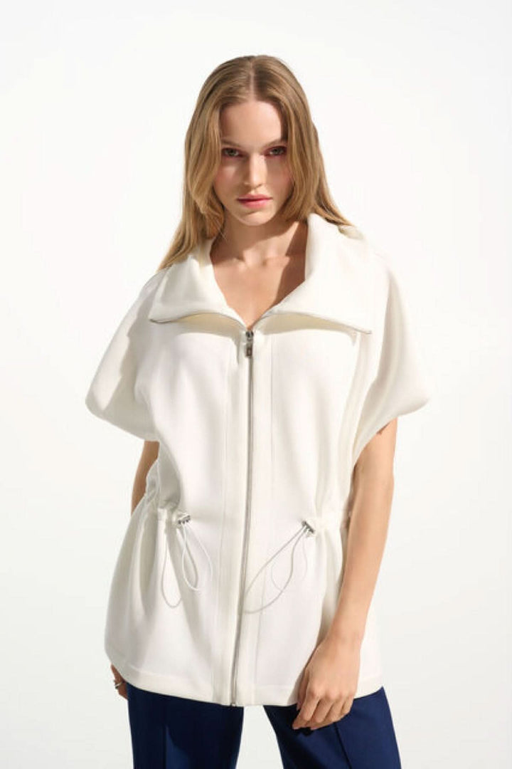 Femme portant une veste zippée à col large avec manches courtes et taille ajustable, équilibre entre style décontracté et raffinement.