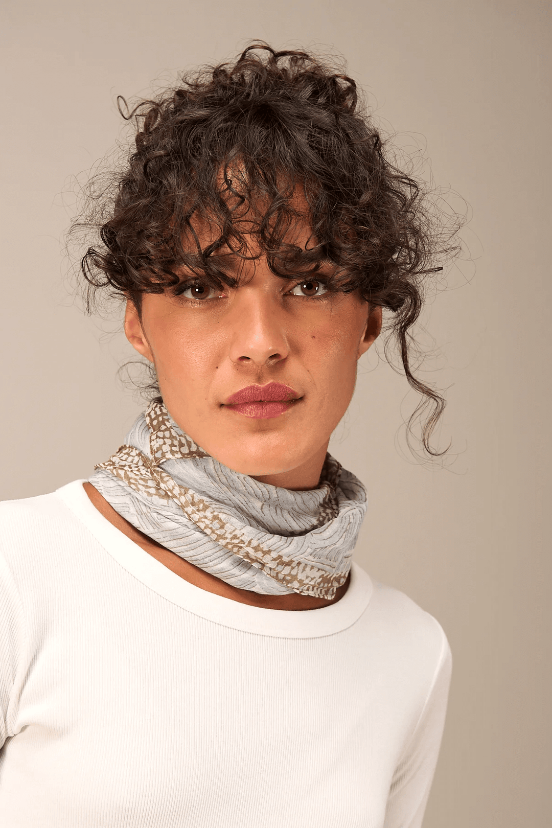 Foulard imprimé porté autour du cou, texture légère et fluide, motif subtil, conseillé avec un chandail uni pour un style polyvalent.