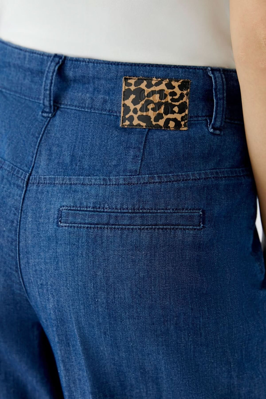 Détails du pantalon en denim à jambe large avec étiquette imprimée léopard à l'arrière.