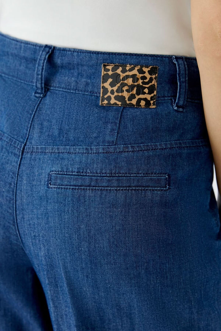 Détails du pantalon en denim à jambe large avec étiquette imprimée léopard à l'arrière.