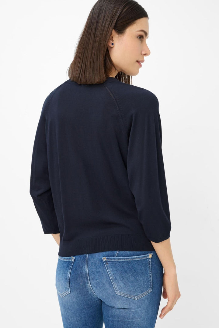 Femme portant un cardigan navy en maille fine, vue de dos, avec un jean ajusté, montrant une silhouette élégante.