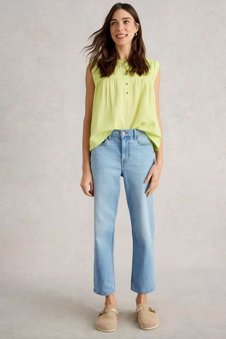 Femme portant un jean coupe droite classique en denim souple avec un haut vert, montrant une silhouette épurée et intemporelle.