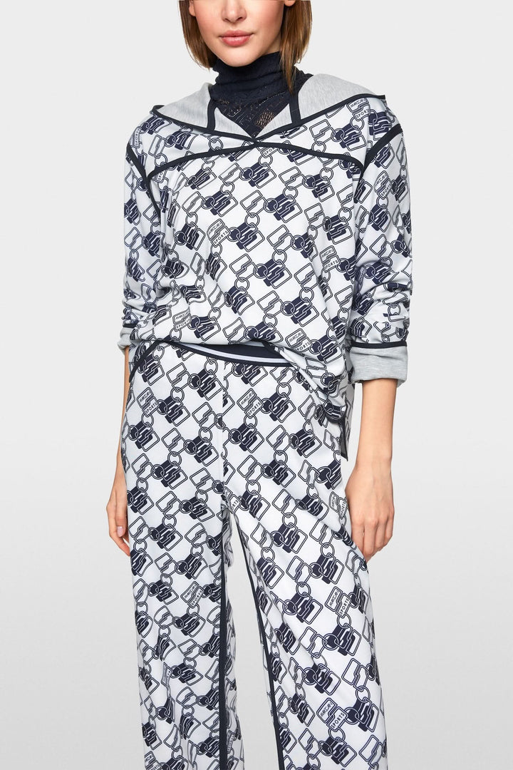 Chandail à capuche réversible avec motif géométrique moderne, porté avec un pantalon coordonné.