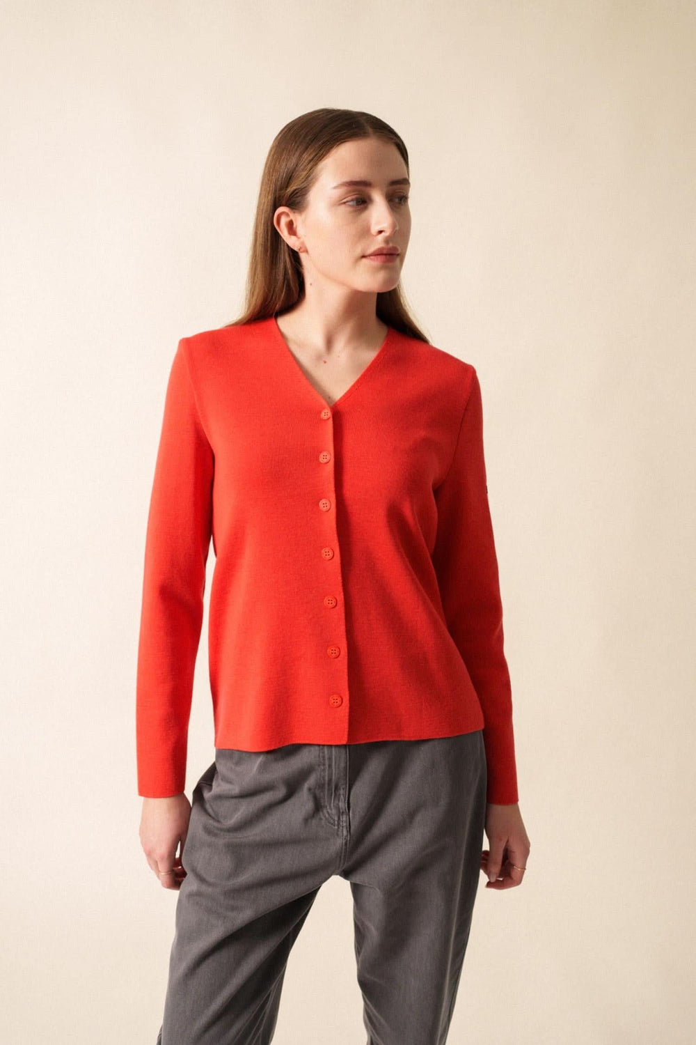 Gilet en laine doux à encolure en V, boutons discrets, porté avec pantalon gris, style élégant et minimaliste.